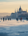 Locals enjoy a day of ice-skating and hockey on the frozen surface of the Danube River in Budapest, against a backdrop of the city's iconic parliament building.