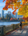 Autumn colors in Stanley Park with cyclists and joggers on the seawall, Vancouver skyline in the distance.