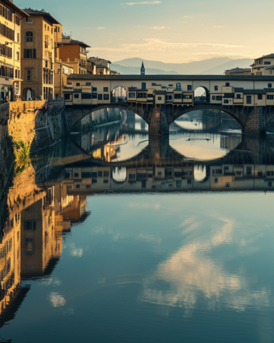 Early morning on Ponte Vecchio in Florence, with pedestrians and cyclists, the Arno river reflecting colorful old buildings.